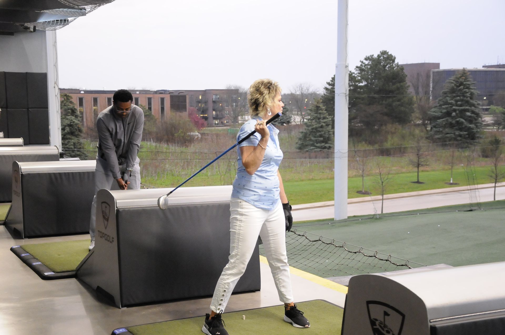 A man and a woman are playing golf on a driving range.