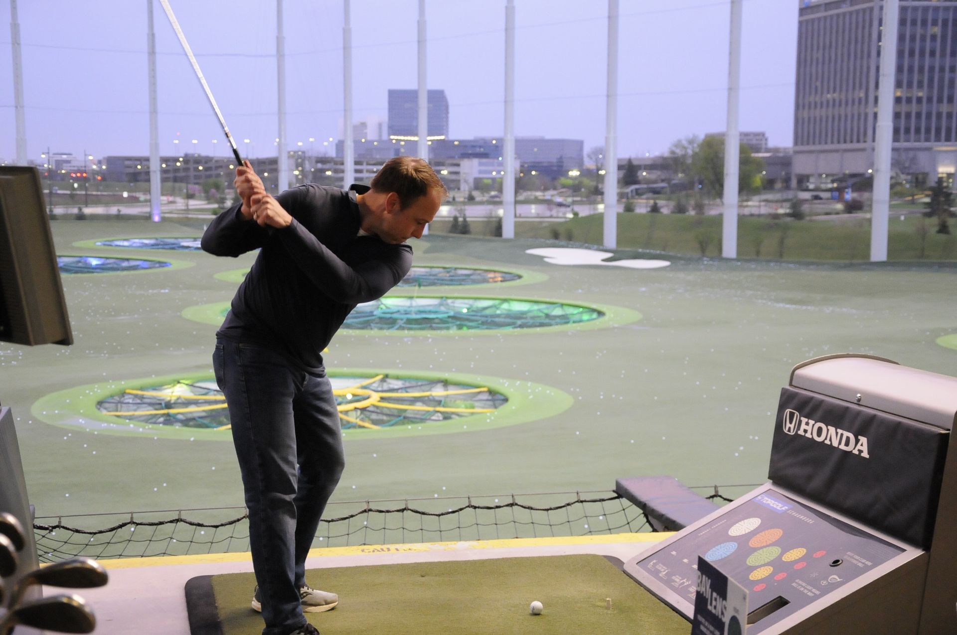 A man is swinging a golf club on an indoor golf course