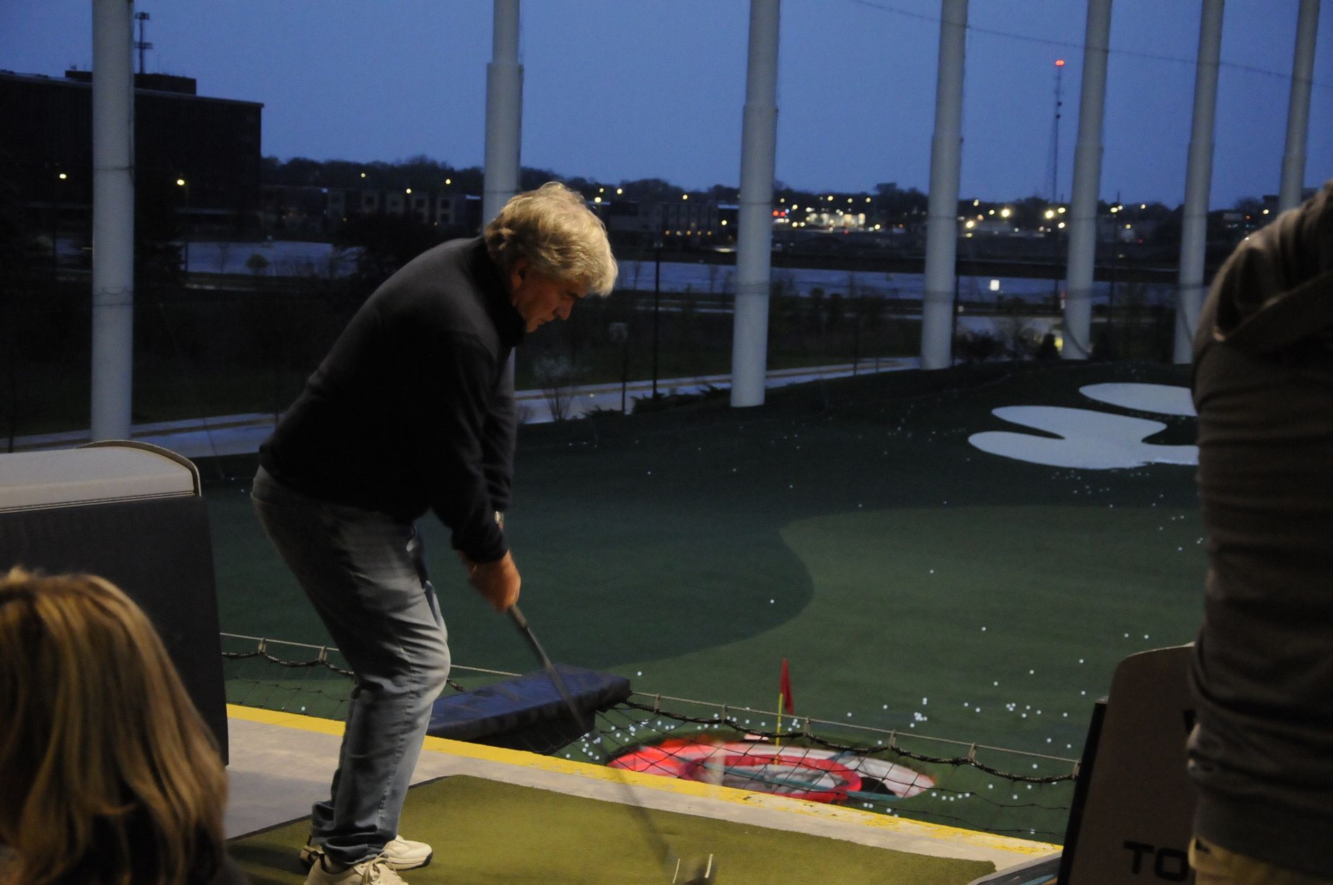 A man is swinging a golf club on a driving range.