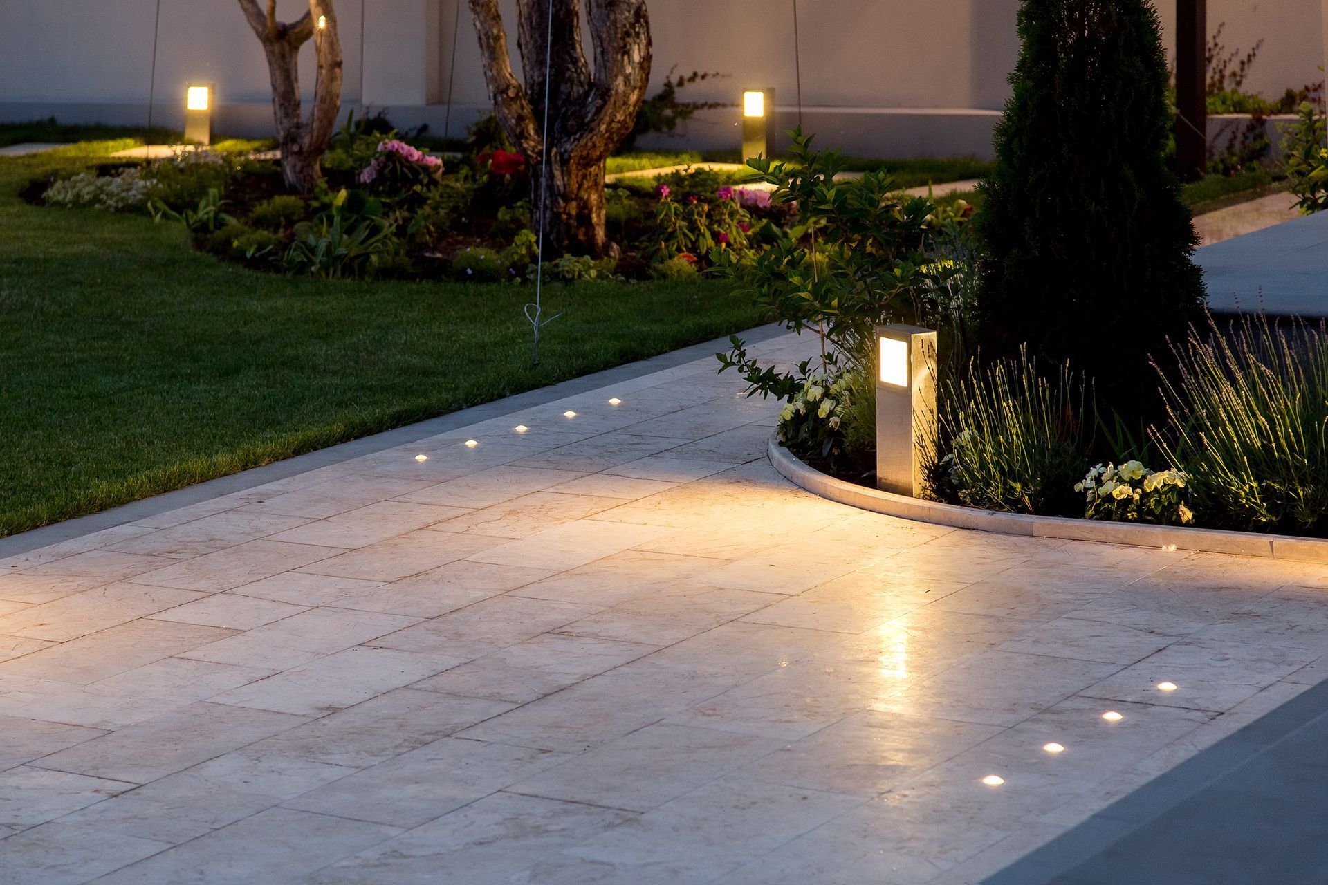 a driveway is lit up at night in a garden