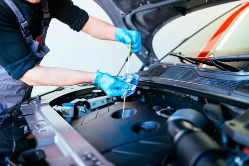 A man is working on the engine of a car with the hood open.