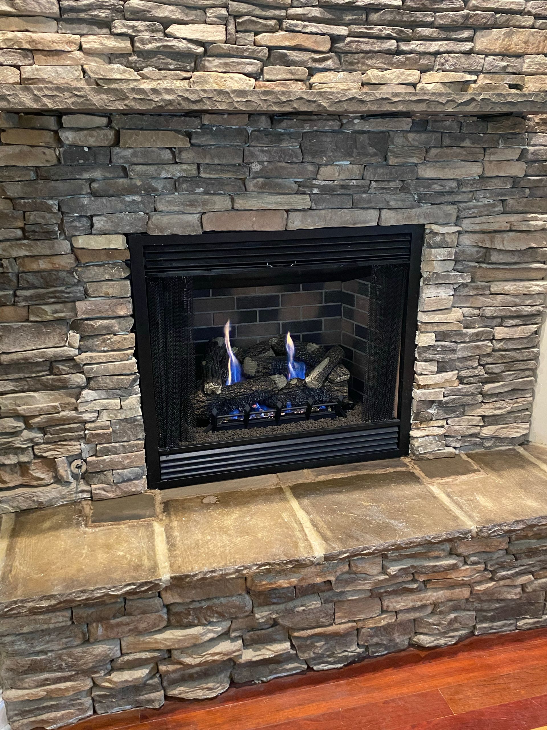 Fireplace with blue flames and stone surround.