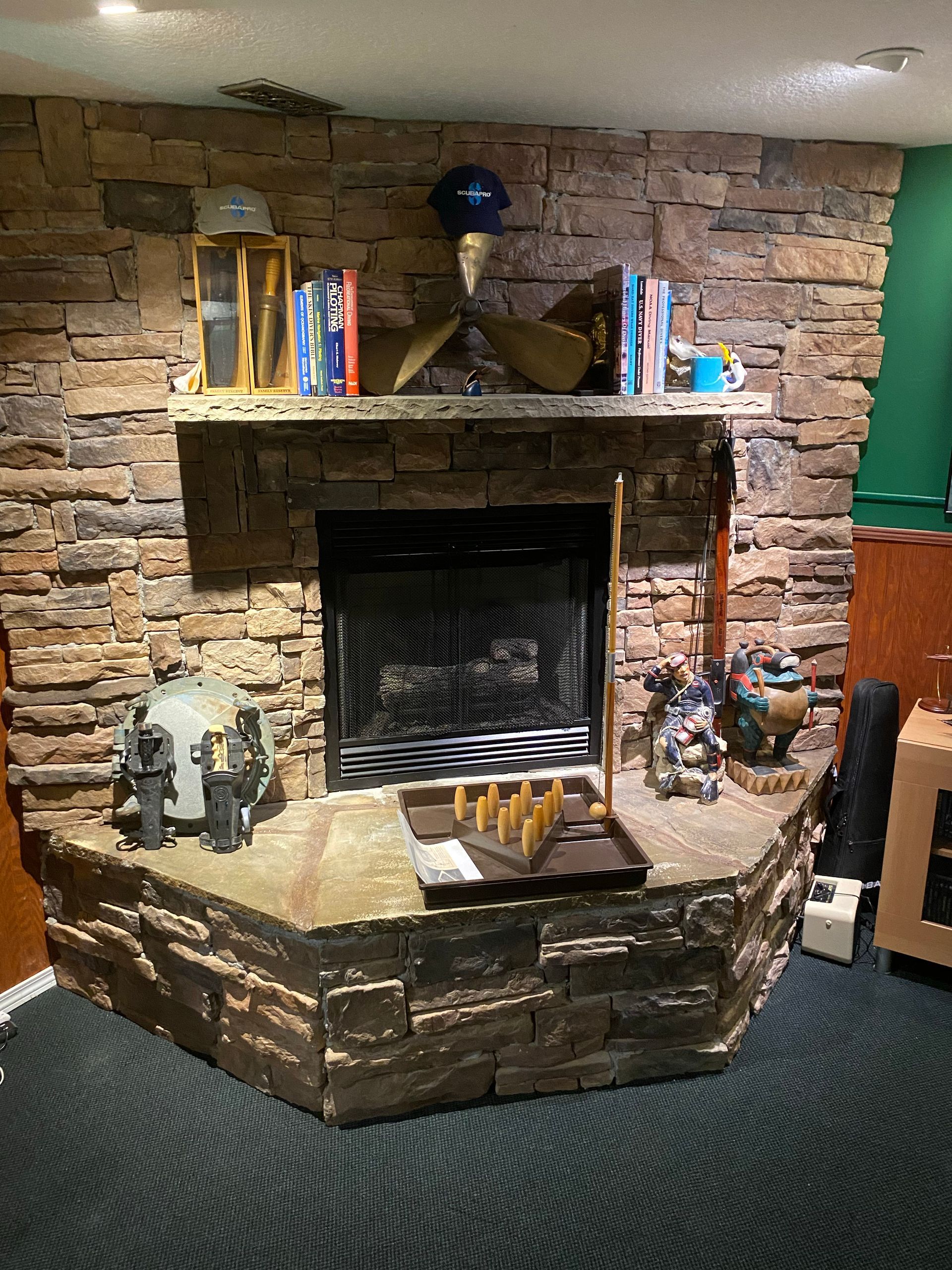 Stone fireplace with mantel, books, and decorative items.