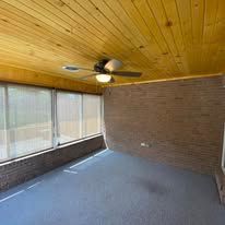 Wooden ceiling with a ceiling fan, brick wall, and blue floor.
