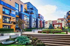 Colorful modern apartment buildings with landscaping and benches on a sunny day.