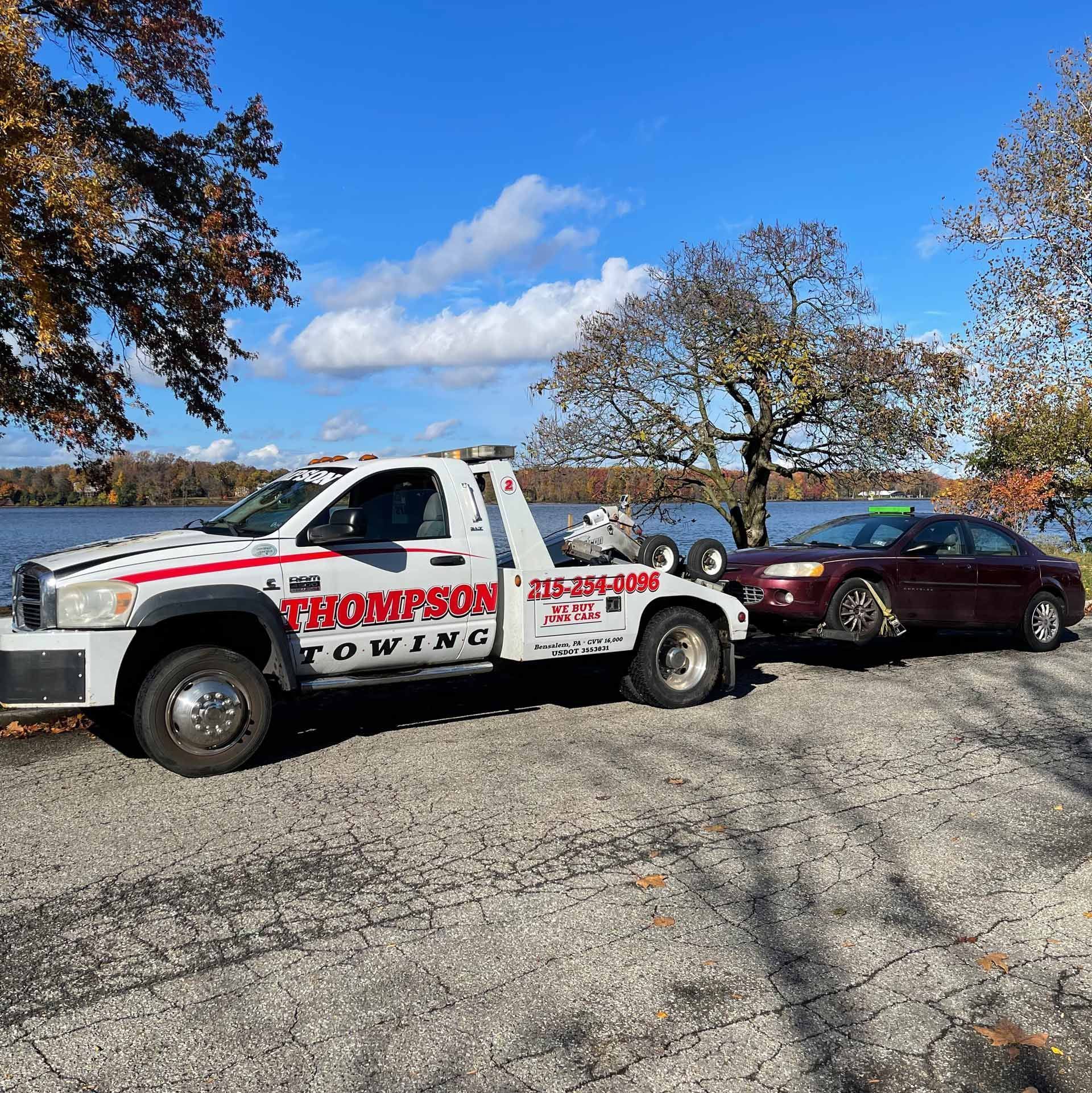 A Thompson towing truck is towing a junk car in Philadelphia