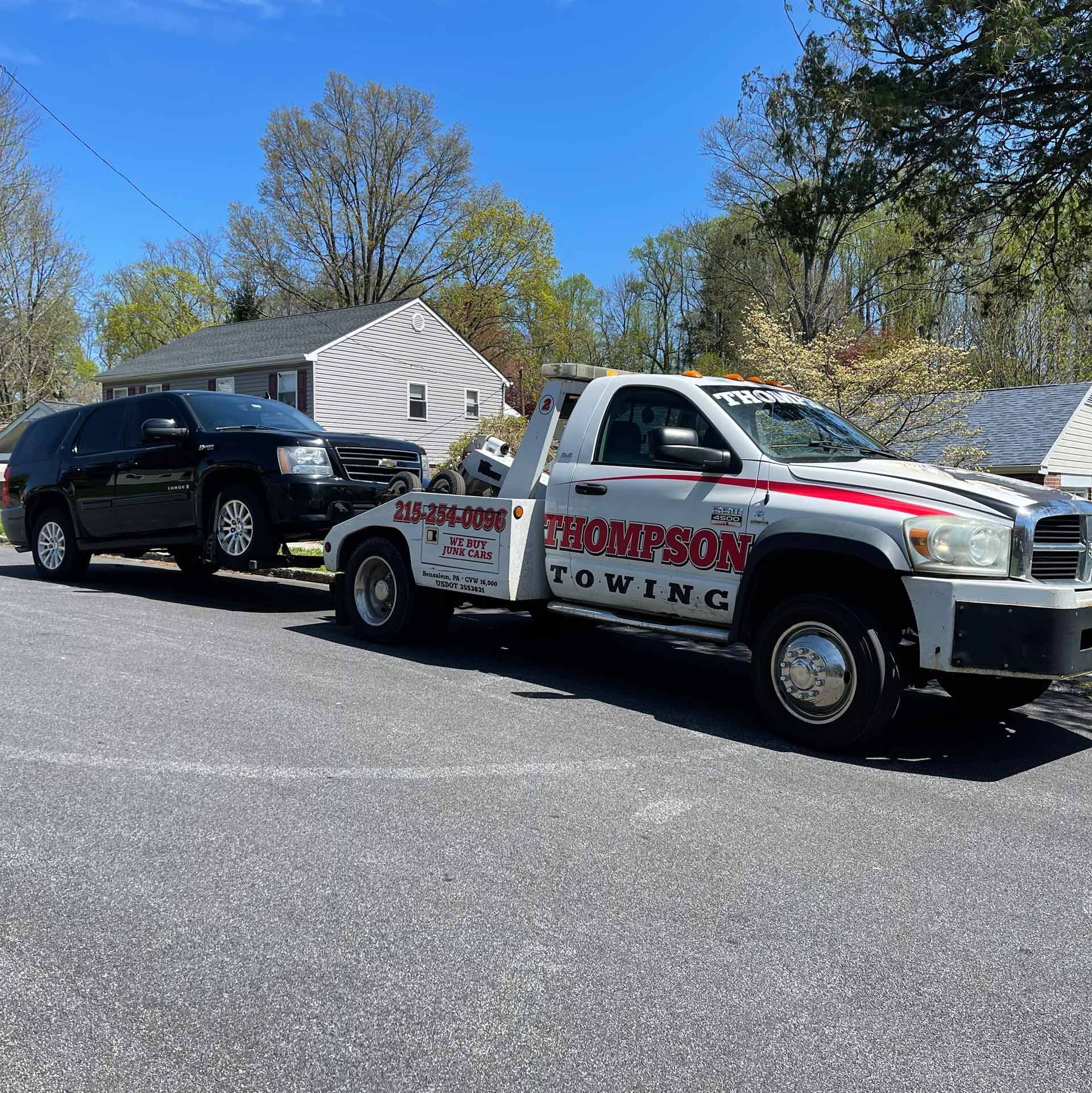 Thompson towing truck towing a junk car in Bucks County