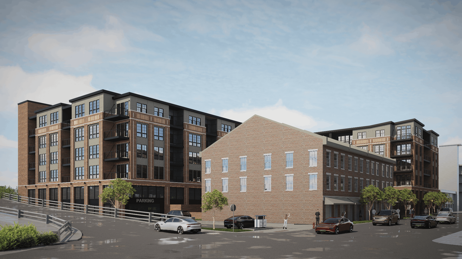 Exterior view of a multi-story brick apartment complex with balconies and parked cars.