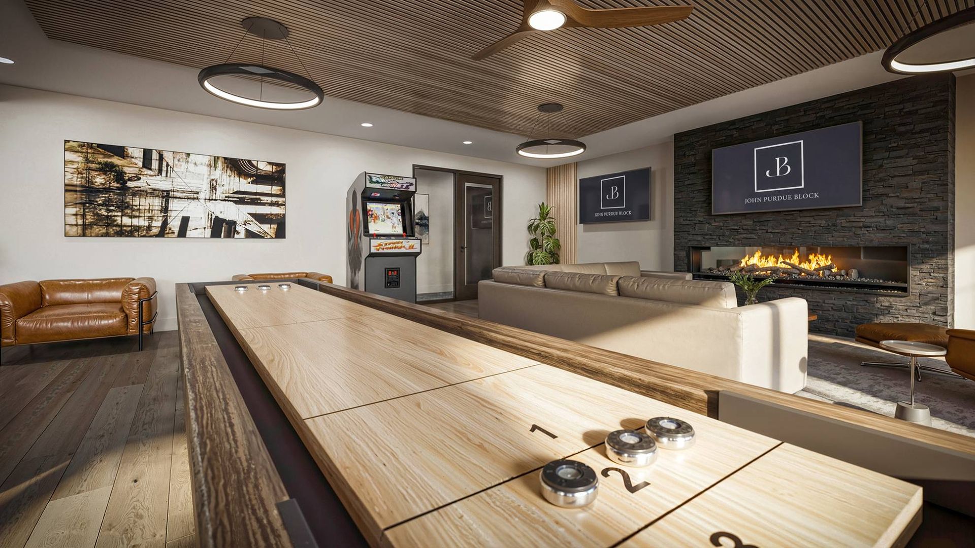 Indoor community lounge with a long shuffleboard table, couches, arcade game, and a fireplace.