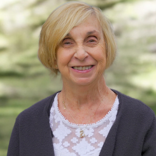 A woman with blonde hair and a white shirt is smiling for the camera.