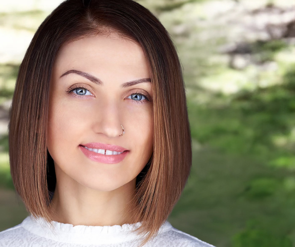 A woman with short brown hair and blue eyes is smiling for the camera.