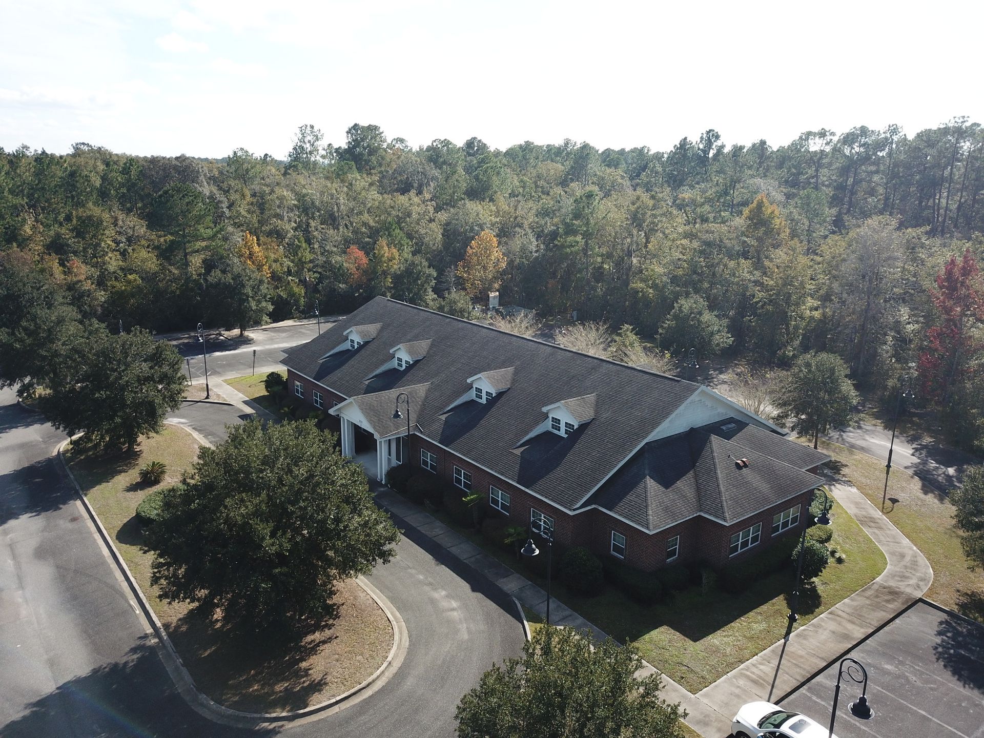 An aerial view of a large building surrounded by trees and a parking lot.