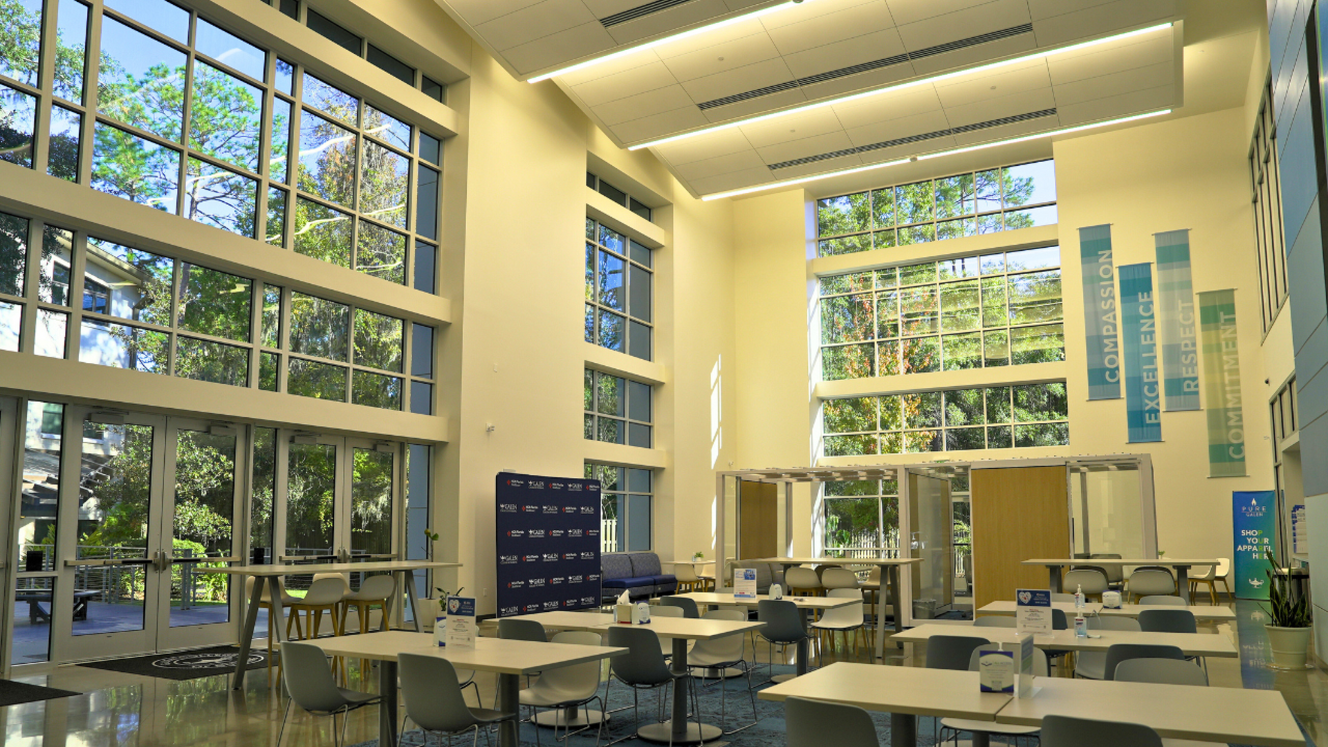 A large room with lots of windows and tables and chairs.