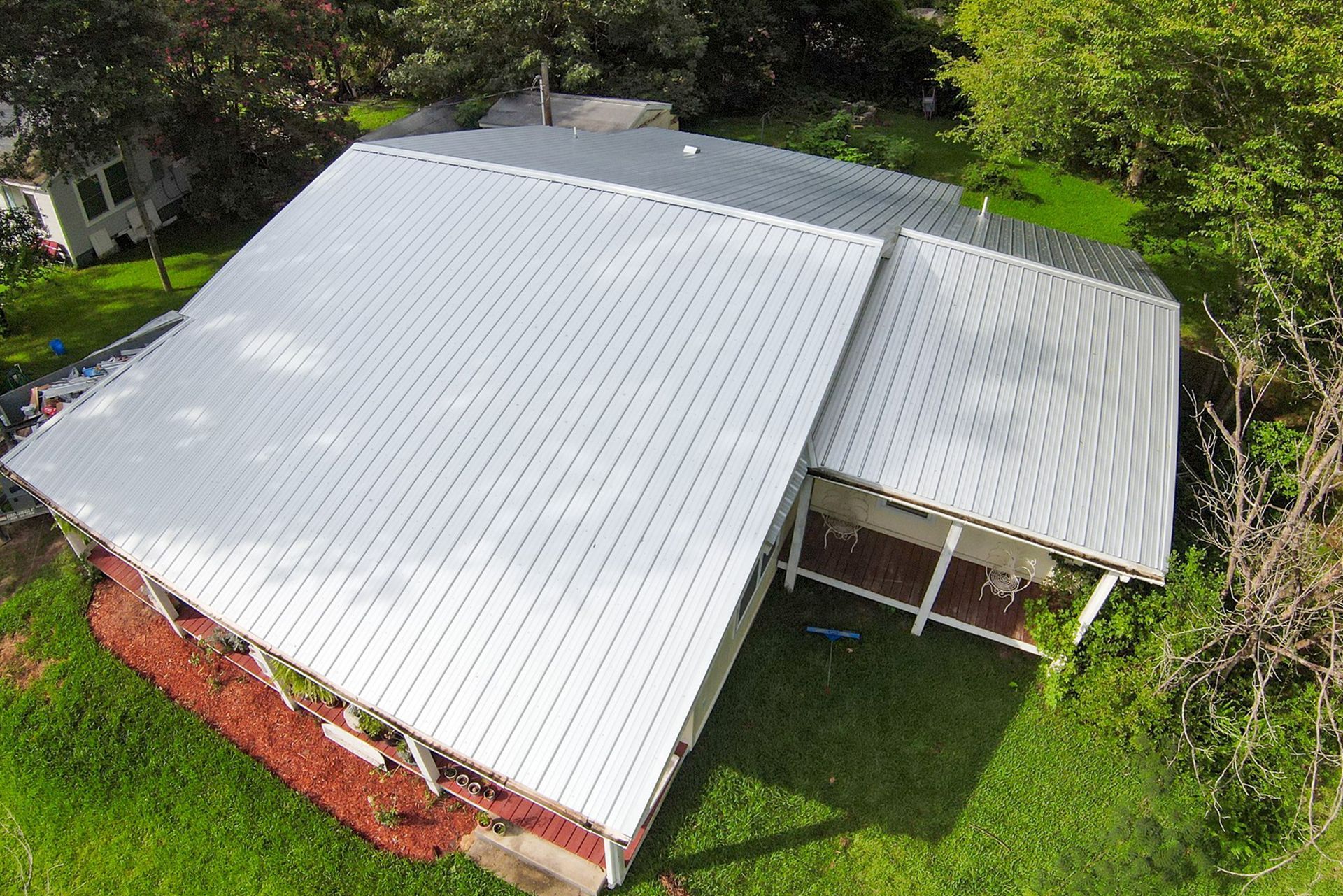An aerial view of a house with a white metal roof.