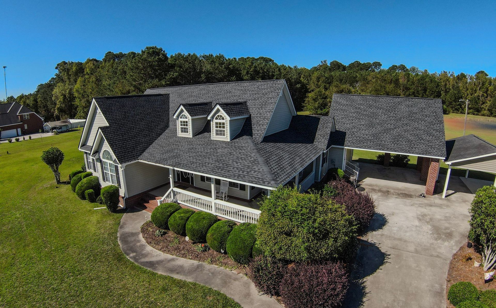 An aerial view of a large white house with a gray roof surrounded by trees.