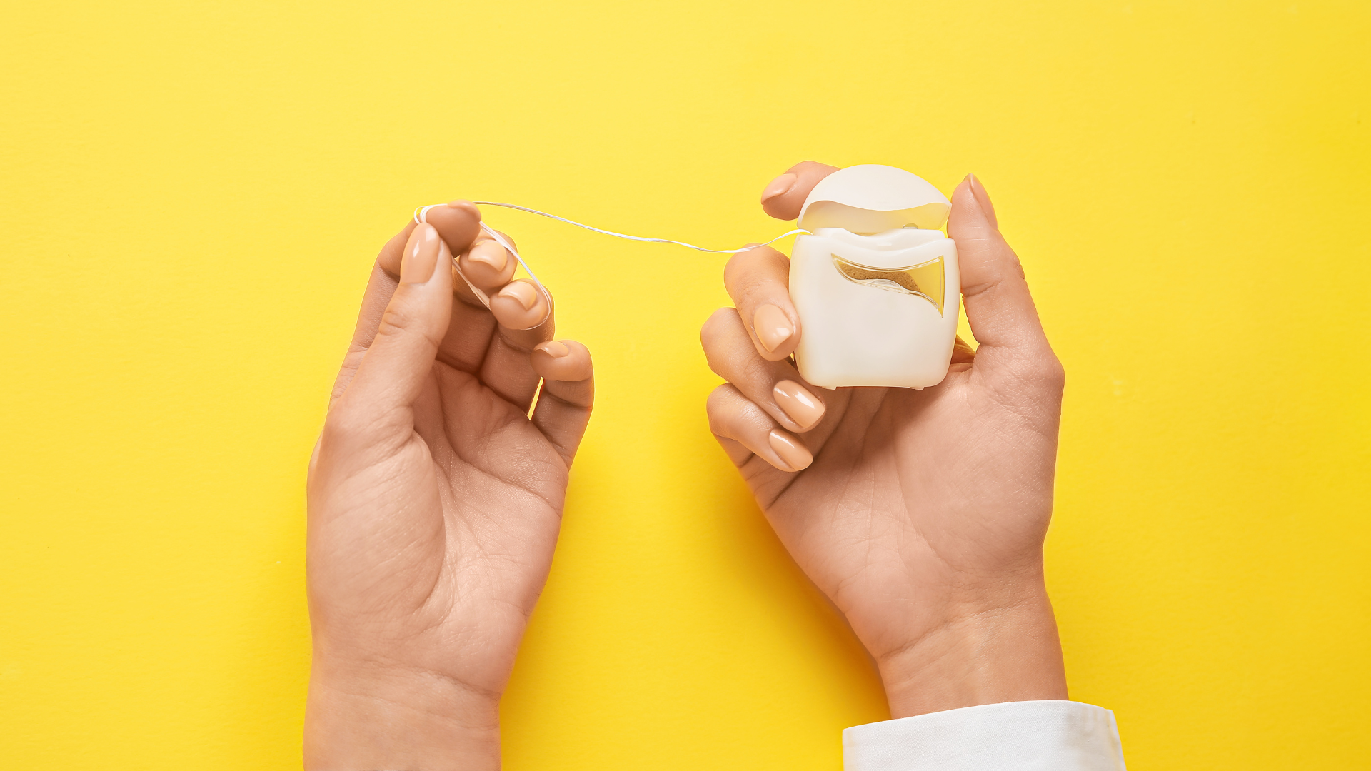 hands holding a floss with a yellow background