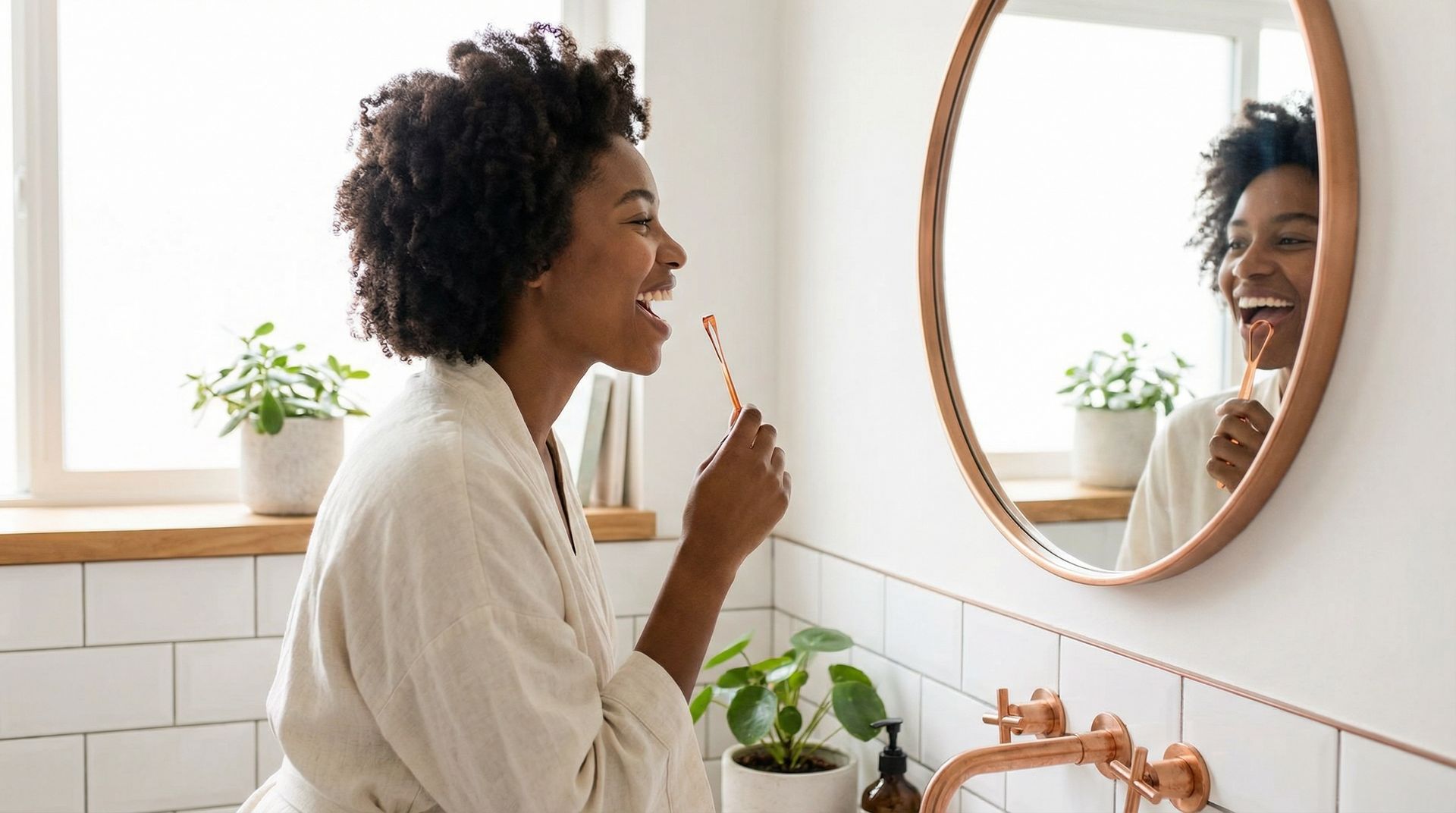 A person smiling while brushing their teeth in front of a round bathroom mirror.