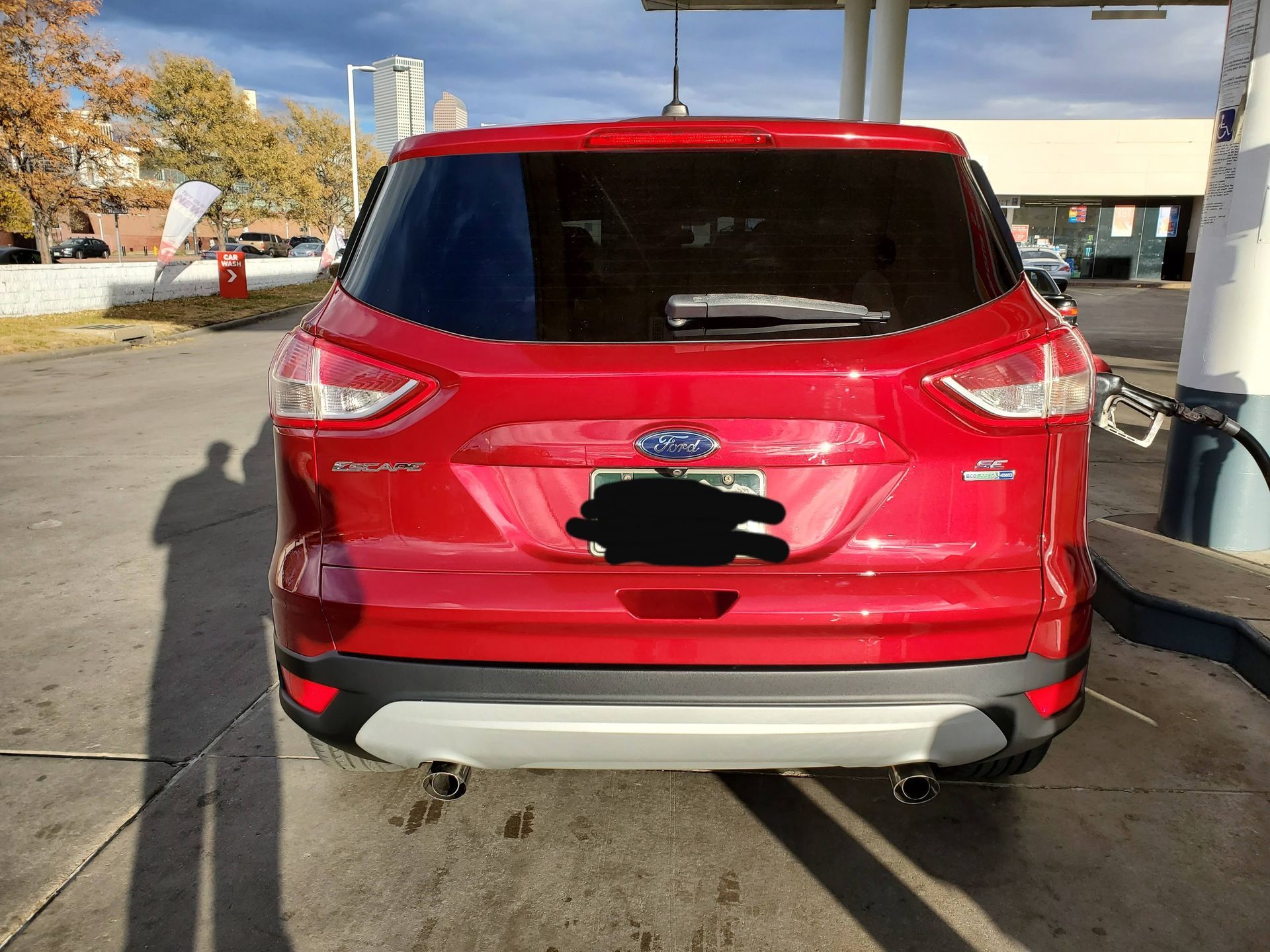 A red Ford Escape SUV parked at a gas station, viewed from the rear.