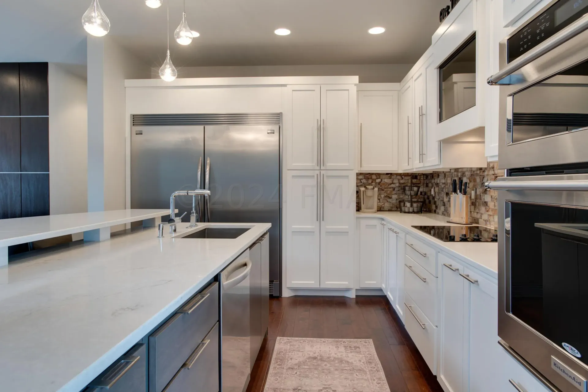 A kitchen with white cabinets and a large island in the middle.