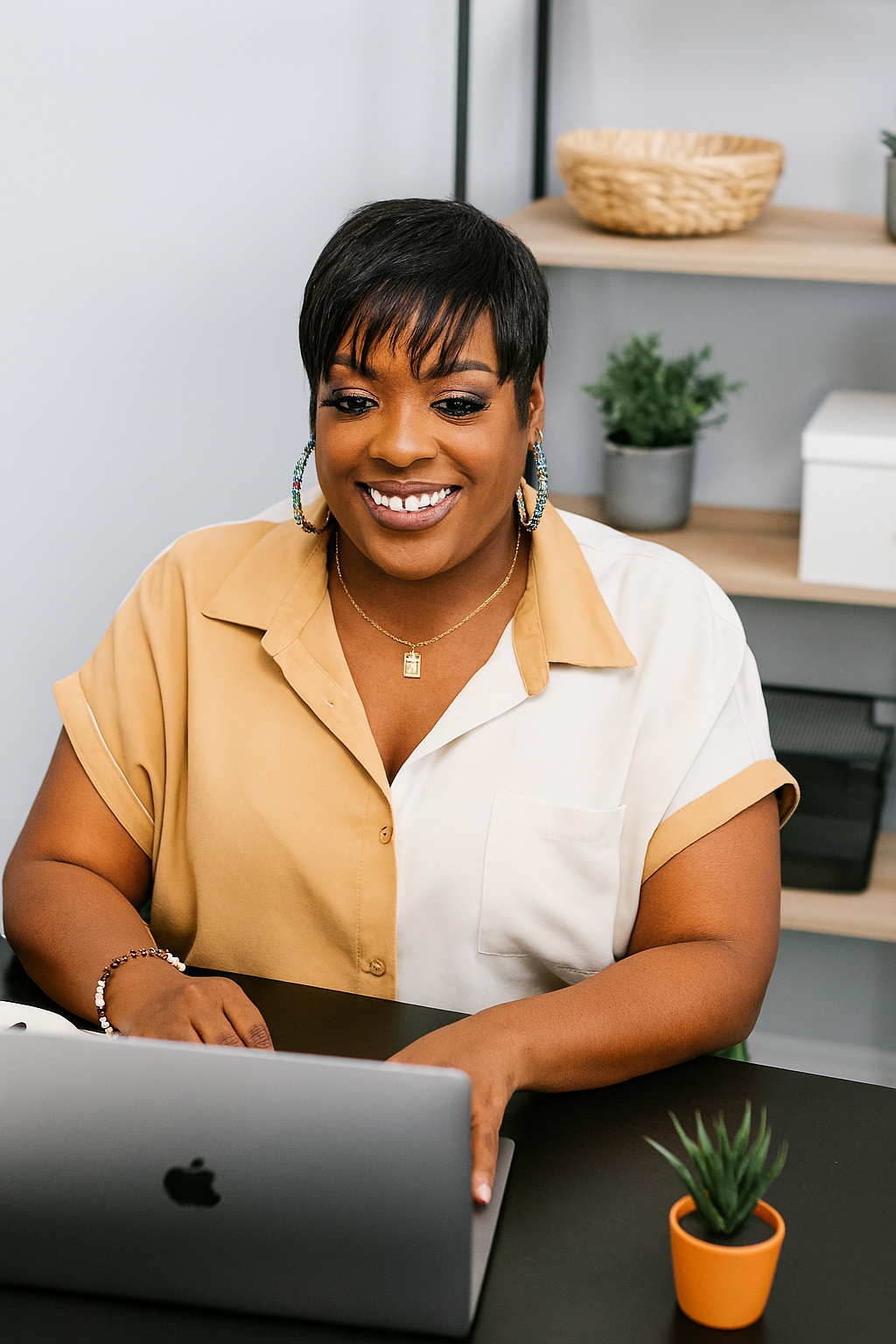 A woman is sitting at a desk using a laptop computer.