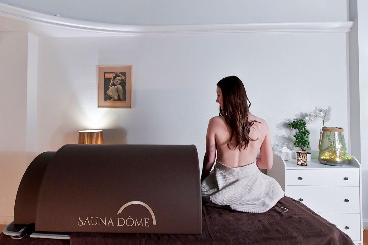 Une femme enveloppée dans une serviette est assise sur un lit dans une pièce.