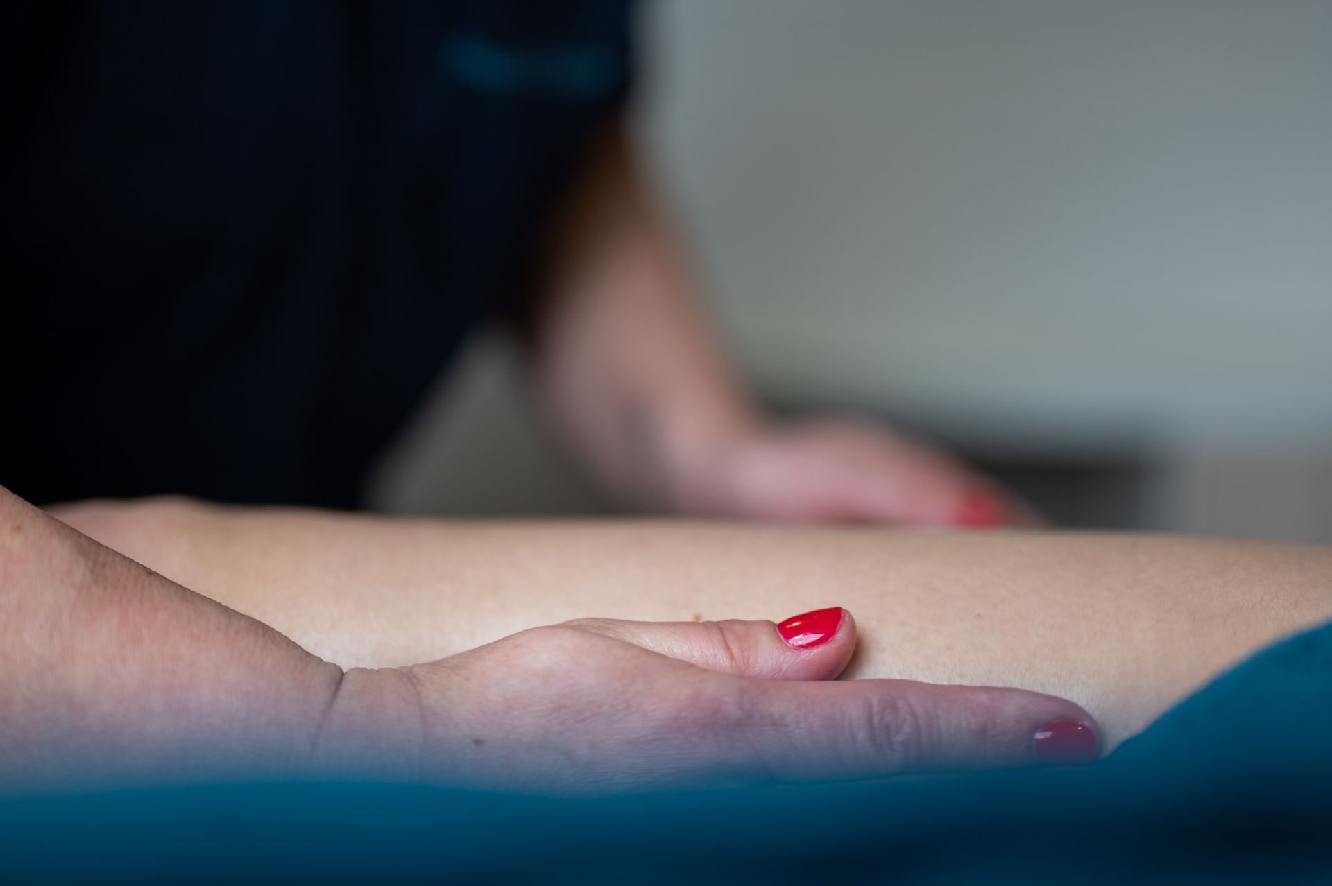 Une femme aux ongles rouges se fait masser la jambe.