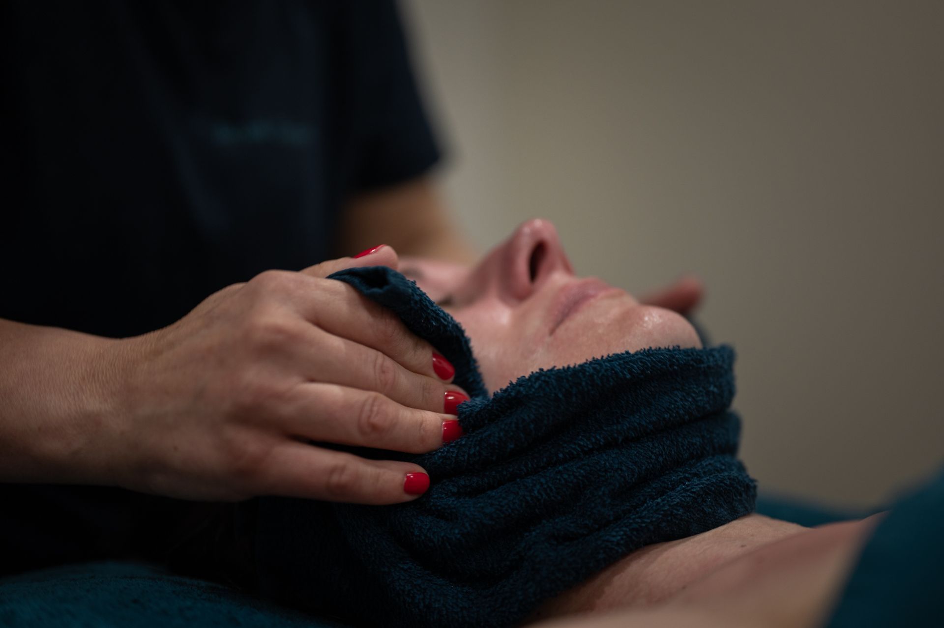 Une femme reçoit un massage du visage avec une serviette autour du cou.