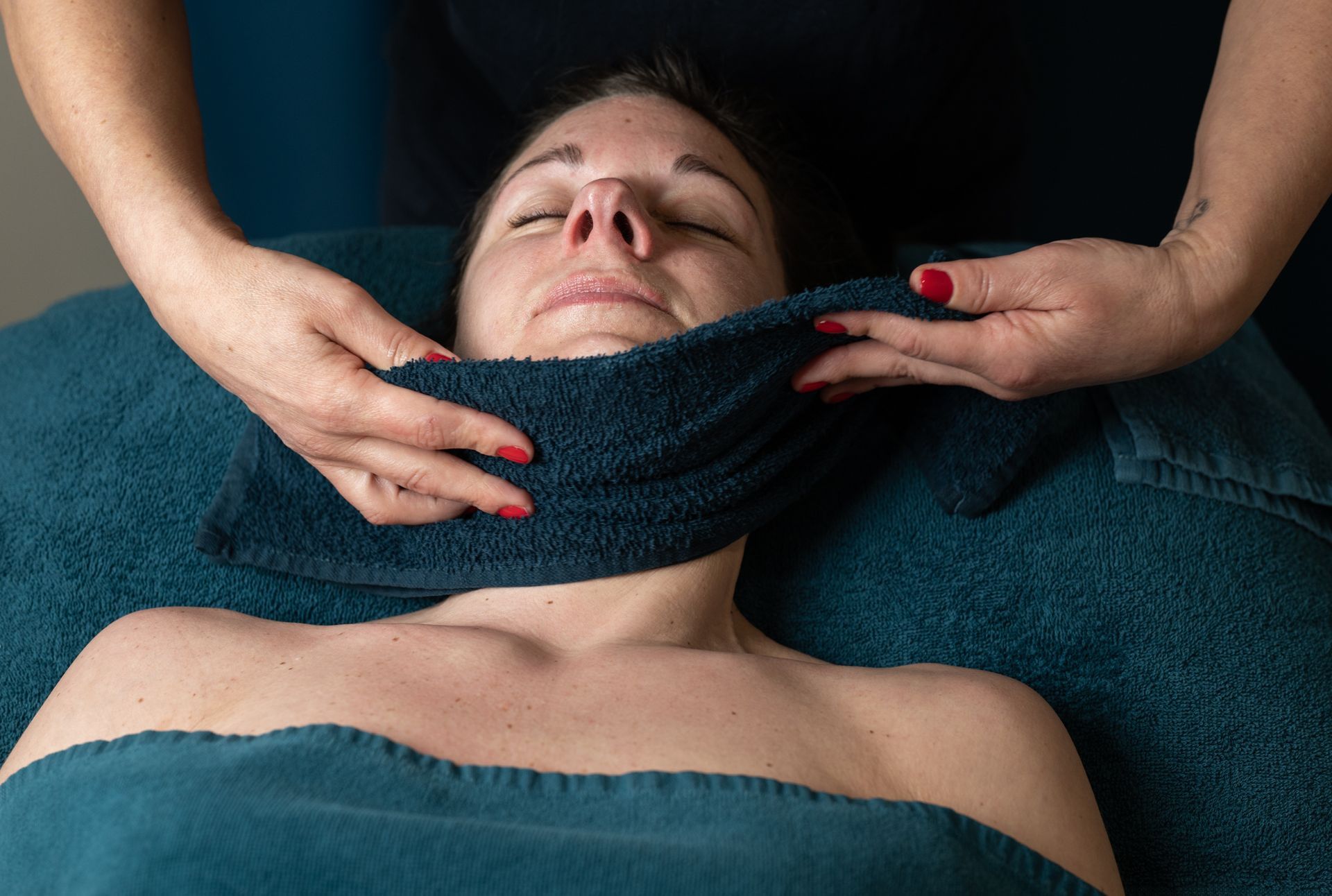 Une femme reçoit un massage avec une serviette autour du cou.