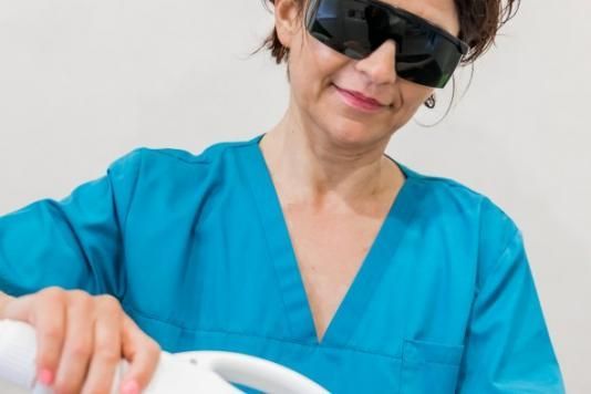 Une femme portant des lunettes de soleil et une blouse bleue tient une machine.
