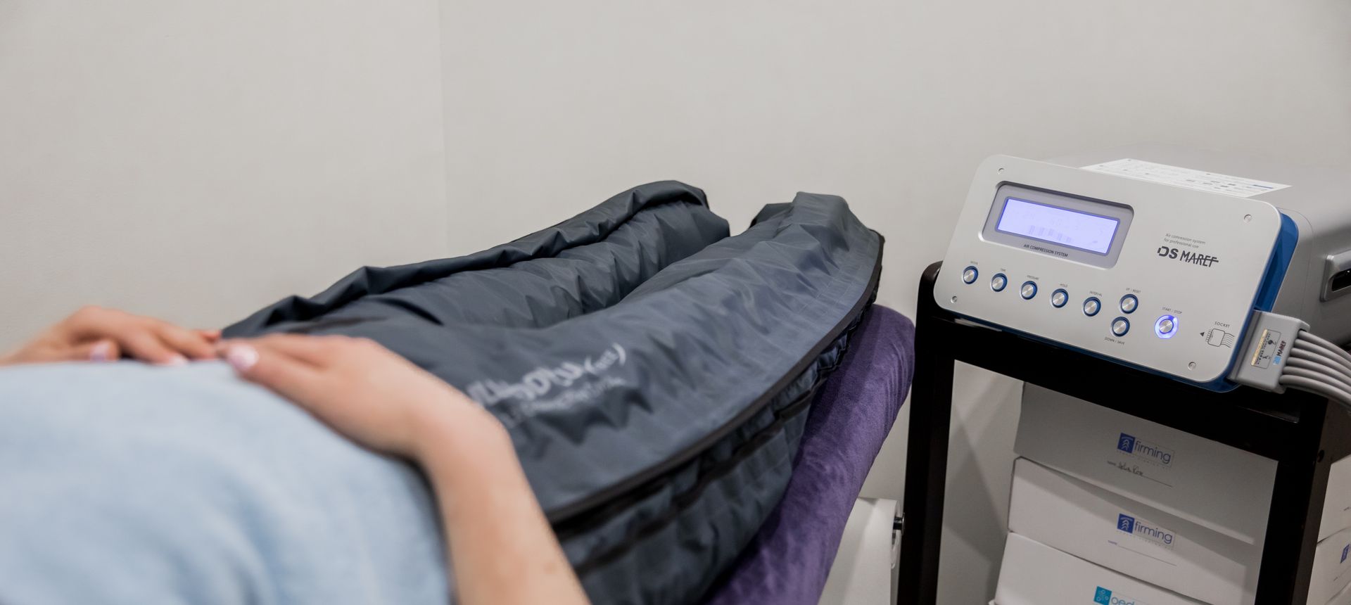 Une personne est allongée sur un lit avec une machine sur ses jambes.