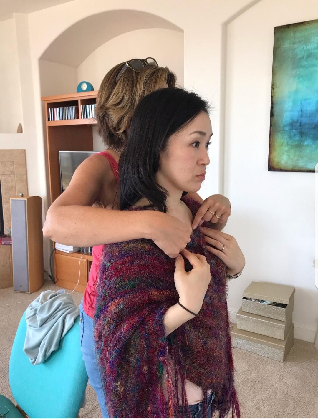A woman is helping another woman with her scarf around her neck