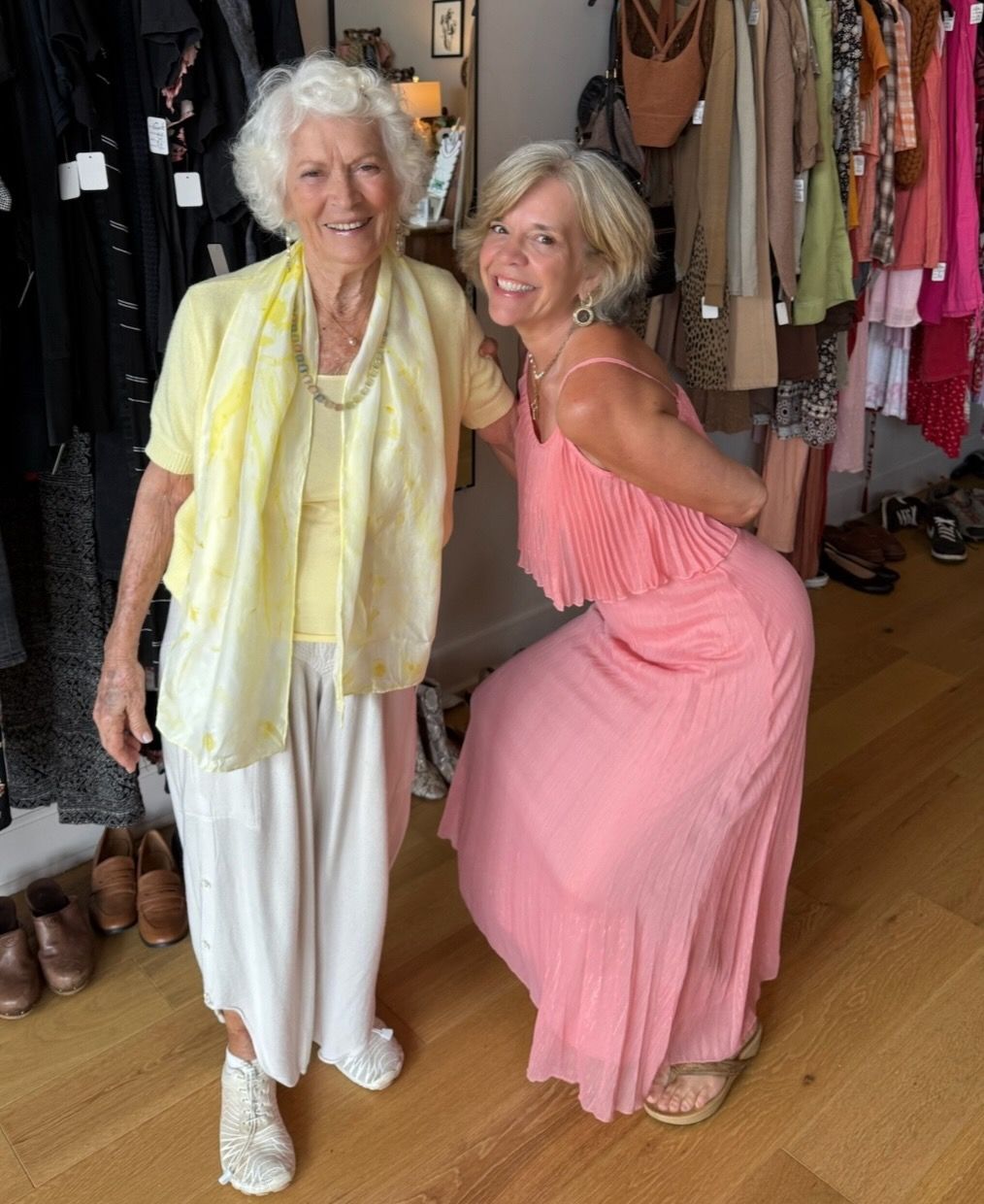 Two women are posing for a picture in a clothing store.