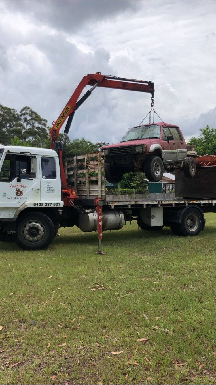 A Truck With a Crane Attached to It is Towing a Car — Hastings Scrap Metal Recyclers in Wauchope, NSW