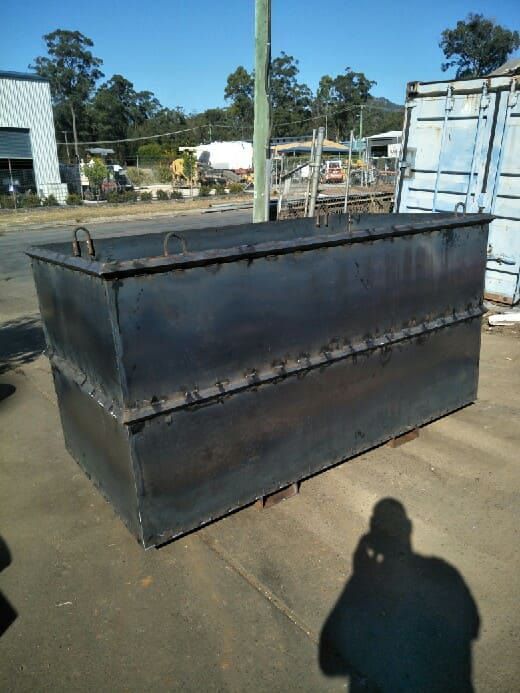 A Large Metal Container is Sitting on the Ground Next to a Blue Container — Hastings Scrap Metal Recyclers in Wauchope, NSW