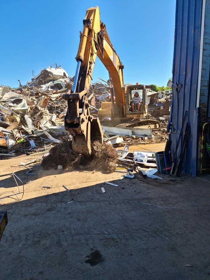 A Yellow Excavator is Digging in a Pile of Scrap Metal — Hastings Scrap Metal Recyclers in Wauchope, NSW
