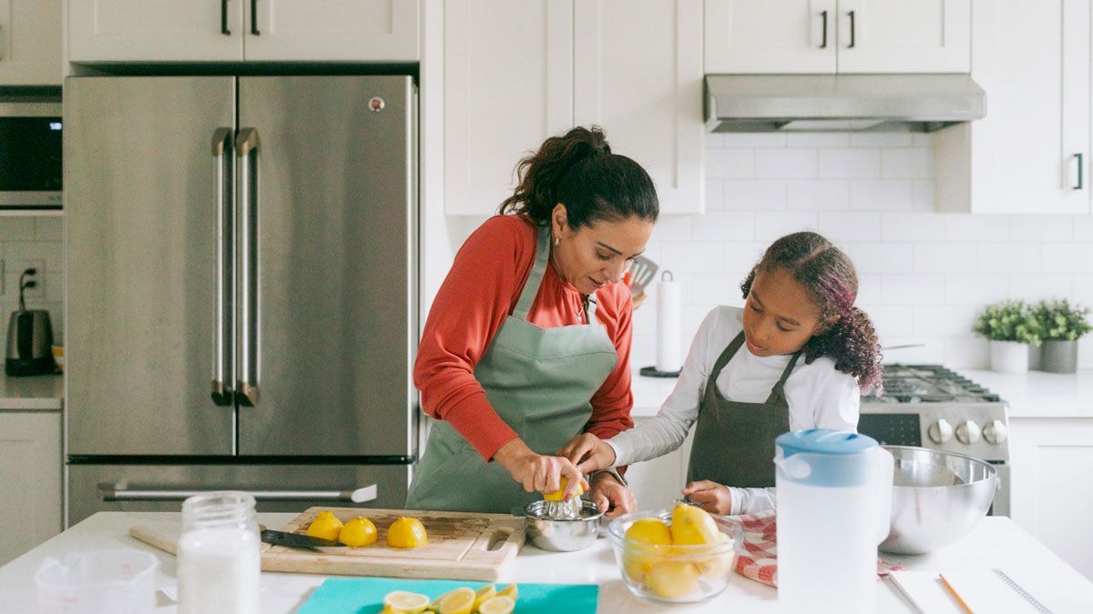 A woman and a child are preparing food in a kitchen.