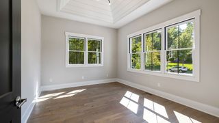 An empty room with lots of windows and hardwood floors.