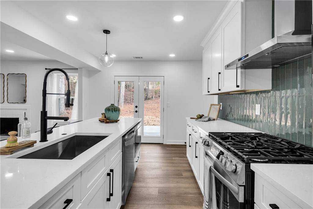 A kitchen with black cabinets , white counter tops , stainless steel appliances and a large island.