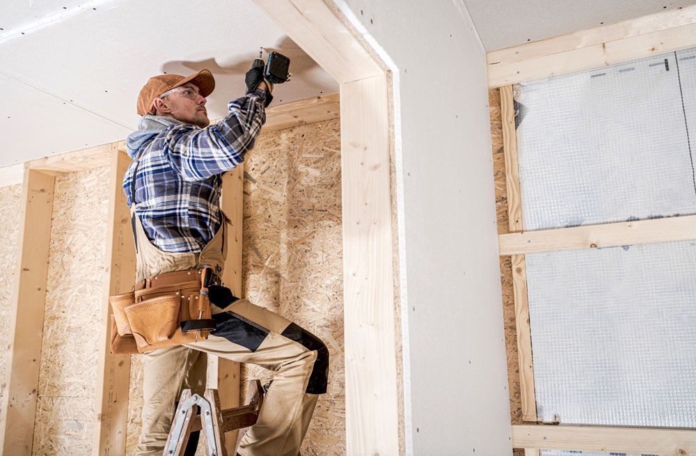 A man is standing on a ladder working on a ceiling.