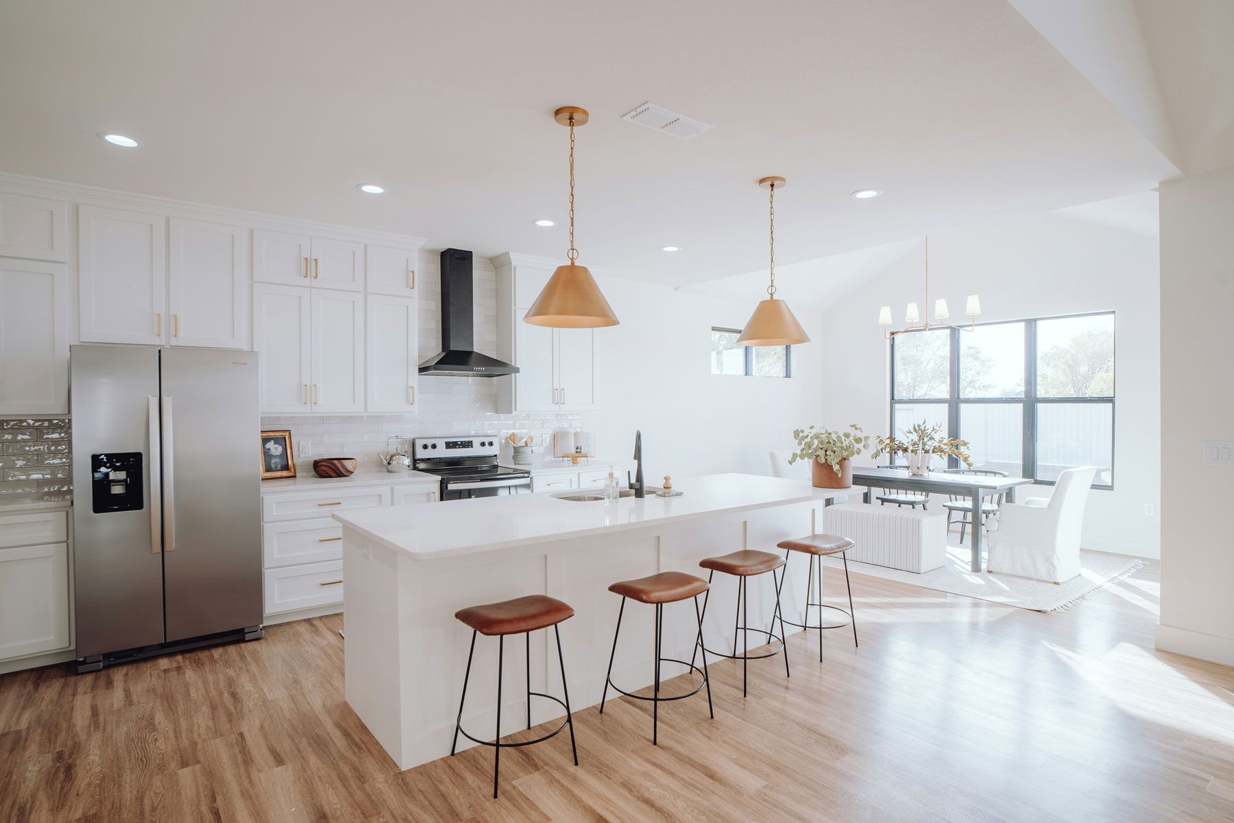 A kitchen with white cabinets , stainless steel appliances , a large island , and wooden floors.