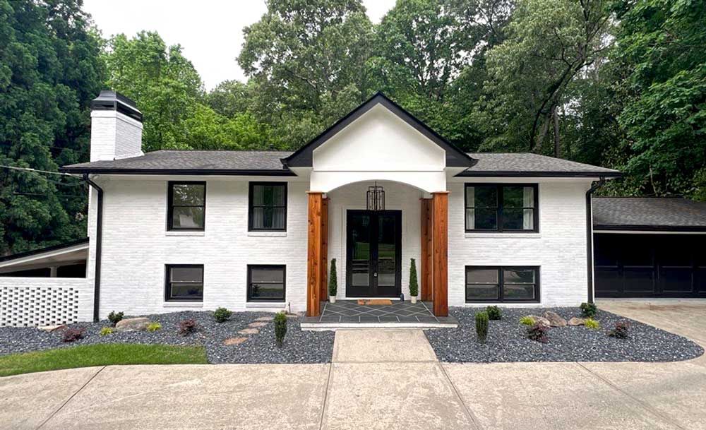 A white house with a yellow door and a gray roof