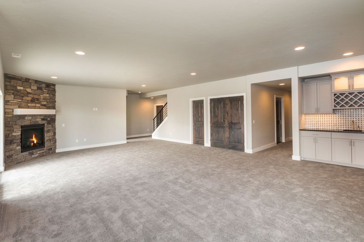 A large empty living room with a fireplace and carpet.