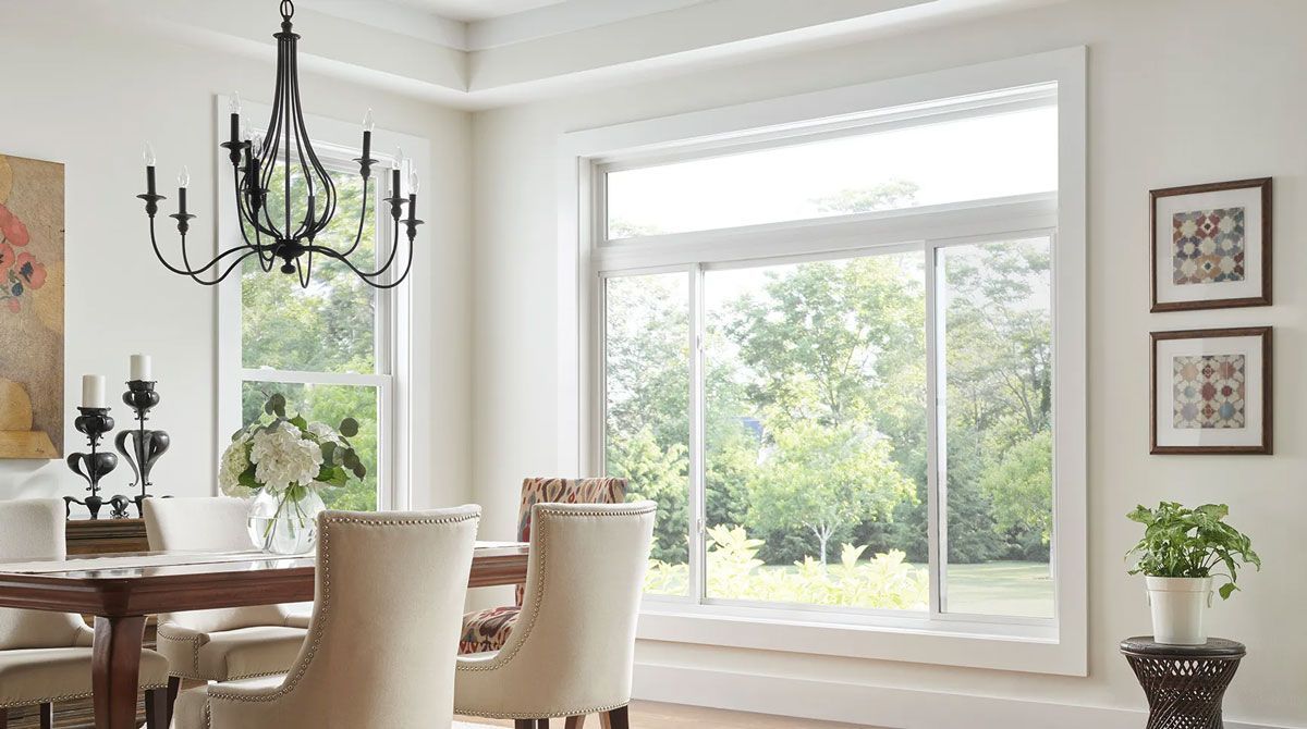 A dining room with a table and chairs and a large window.