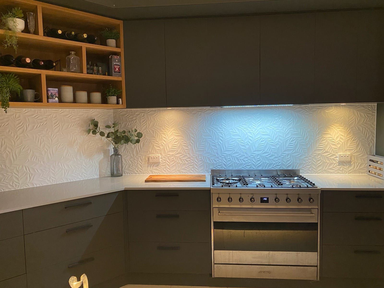 Kitchen with brick wall, blue cabinets, black range, copper cookware, and a wooden island — Cooloola Tile Company in Gympie, QLD