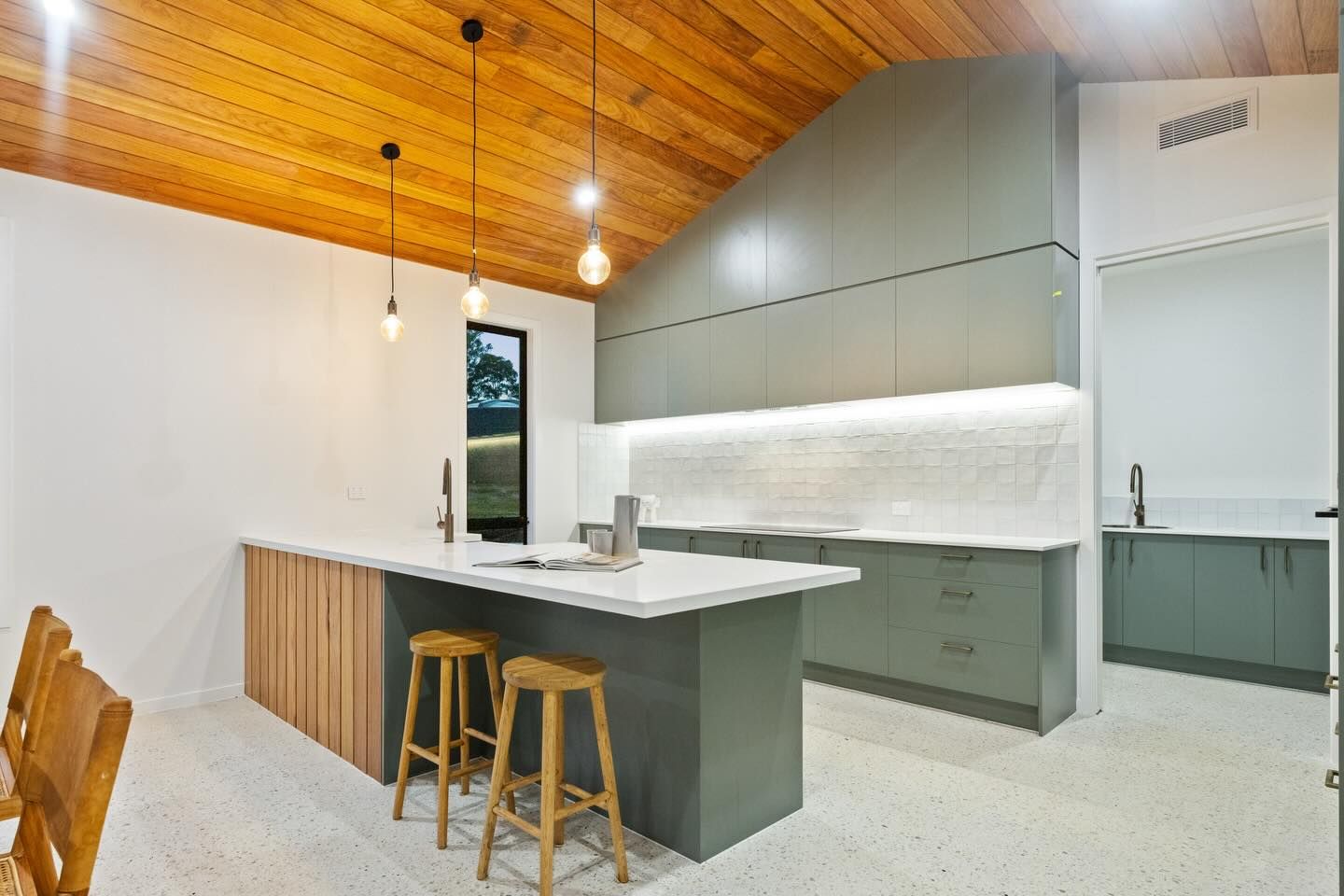 Kitchen and dining area with marble floors, a table with black chairs, and a refrigerator.