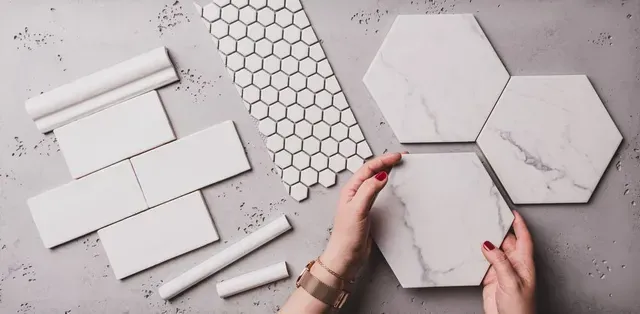 Hands Holding Hexagonal Tiles on a Grey Surface With Various Other Tile Shapes — Cooloola Tile Company in Hervey Bay, QLD