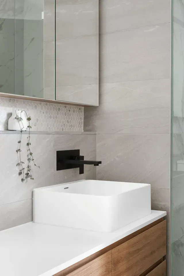 Modern Bathroom With White Sink, Black Faucet, Wooden Cabinet, and Neutral Tile — Cooloola Tile Company in Hervey Bay, QLD