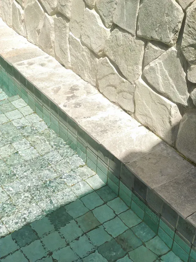 Stone Wall Next to a Tiled Pool With Clear Water — Cooloola Tile Company in Gympie, QLD