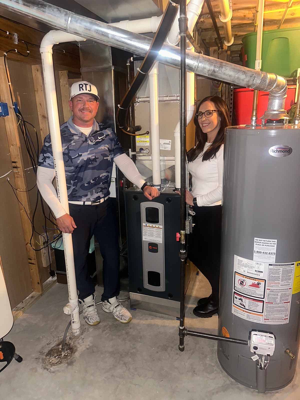 A man and a woman are standing next to an air conditioner outside of a house.