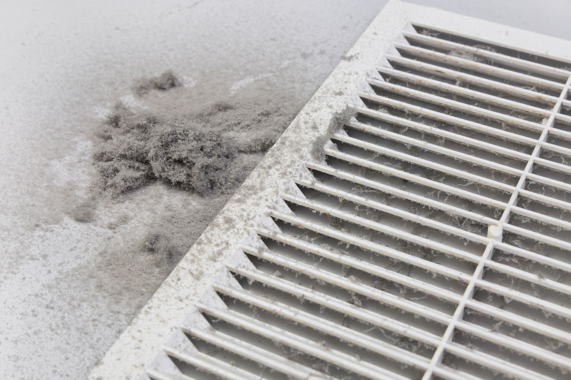 A close up of a dirty air vent with dust on it.